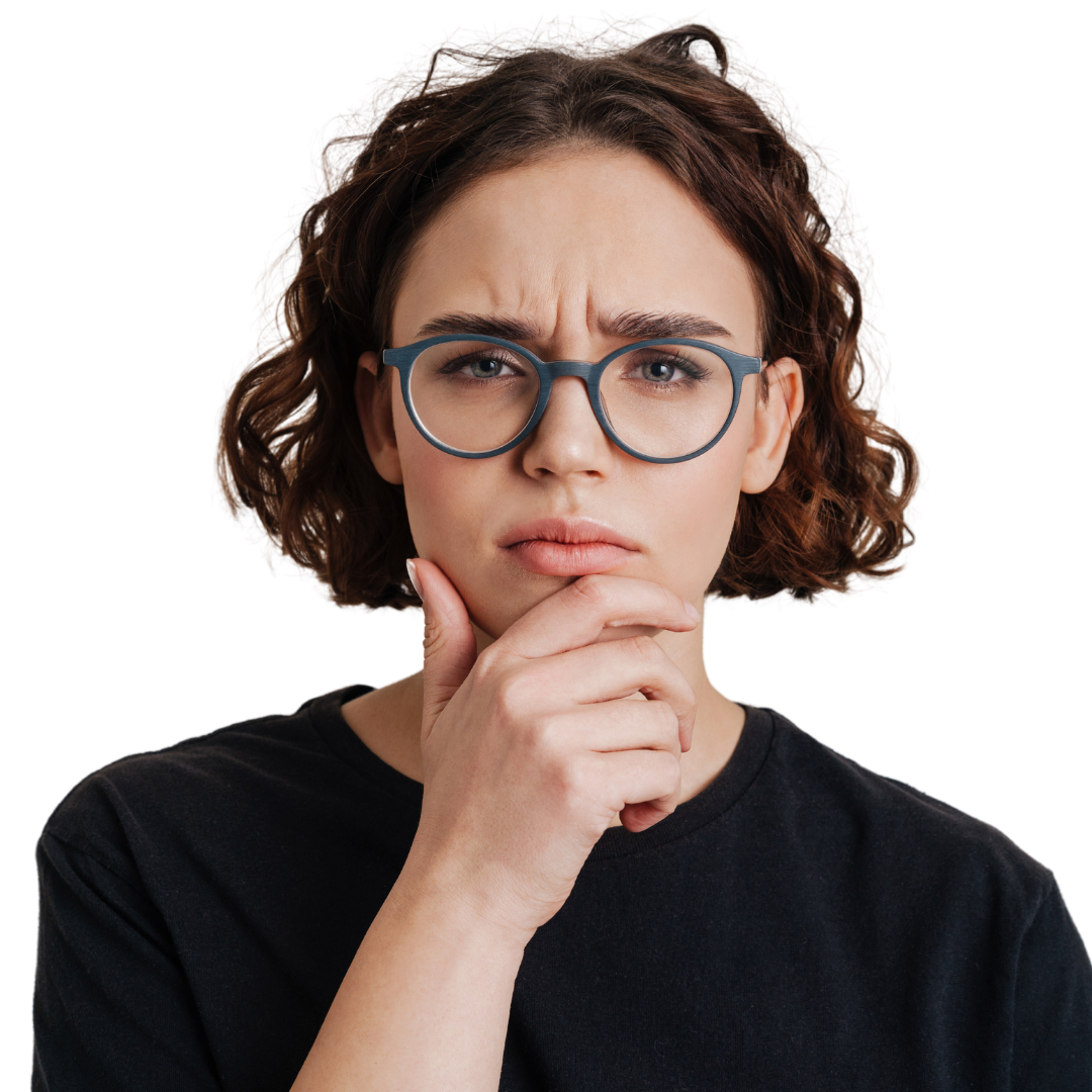 Young woman with short brown curly hair, wearing grey round glasses and a black t shirt looking quizzical.