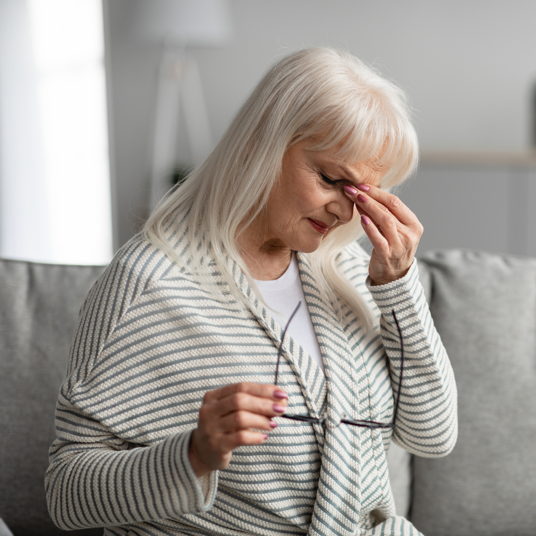 Woman sat on sofa, removed glasses, dry eyes, cataracts. Dry Age-Related Macular Degeneration.