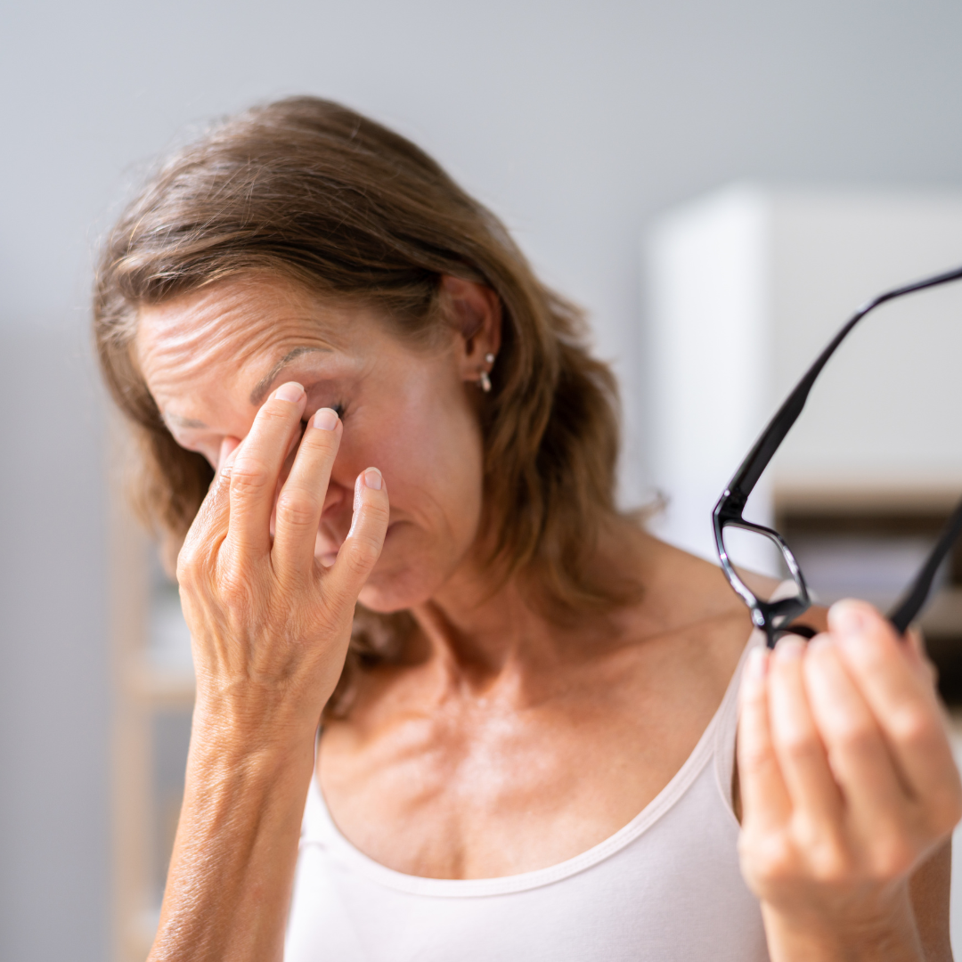 Middle aged woman rubbing eyes and holding glasses